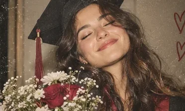 A graduate smiling with eyes closed, holding flowers